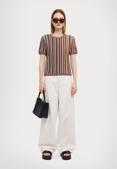 Haut en maille rayé dans plusieurs couleurs, bord noir ; pantalon blanc ample ; sac à main noir ; sandales noires épaisses.