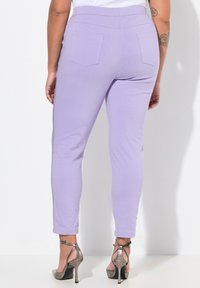 Lavendel tapered byxor i lätt tyg, med en mjuk yta och två bakfickor, i kombination med metalliska högklackade sandaler.