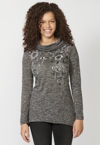 Langärmliges Oberteil mit Kragen in einem dunkelgrauen Melange-Stoff, das auf einer Seite mit weißen Blumenstickereien und einer subtilen Textur versehen ist.