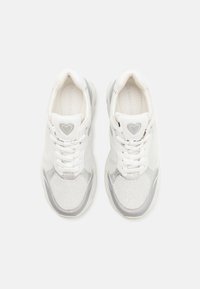 White sneakers with mesh and leather upper, reflective silver accents, round laces, and heart logo on the tongue, featuring a textured sole.