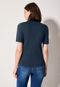 Tmavě modrý top s krátkým rukávem vyrobený z hladké tkaniny, s jednoduchým designem, přiléhavým střihem a kulatým výstřihem.