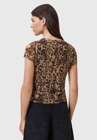 Īss piedurkņu tops ar leoparda raksta rakstu un pieguļošu siluetu, apaļu kakla izgriezumu un mīkstu audumu. Aizmugurē redzami izteikti dzīvnieku raksti.