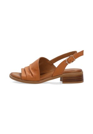 Tanfarvet læder sandal med åben tå, lav stakket hæl, rynket front og justerbar ankelrem med sølvspænde på hvid baggrund.