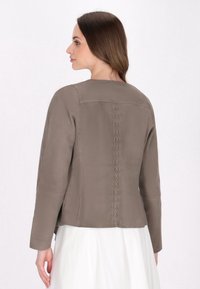 Graue Kunstlederjacke mit langen Ärmeln, die ein schlichtes Design und vertikale Nahtdetails auf der Rückseite aufweist. Glatte Textur.