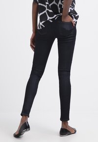 Slim fit jeans i mörk tvättad denim med en slät yta, med bakfickor och en åtsittande siluett. I kombination med svarta balettflat.