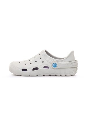 Zueco blanco de goma sin cordones con orificios de ventilación, suela texturizada y correa trasera ajustable con un logo circular azul.