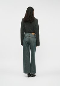 Platais kājstarpes džinsi izbalinātā tirkīza krāsā, ar augstu jostasvietu un divām aizmugurējām kabatām. Apvienoti ar tumši pelēku svārku, minimālisma dizains.