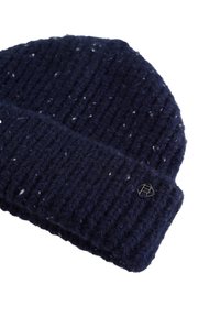 Tengerészkék bordázott kötött sapka fehér foltokkal és egy kis fém logóval a visszahajtott szegélyen.