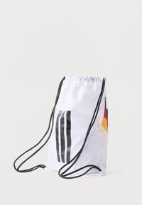 Nahrbtnik s žnalo iz belega najlona, z black grafiko s tremi navpičnimi črtami in barvnim akcentnim vzorcem v rdeči, rumeni in črni barvi.