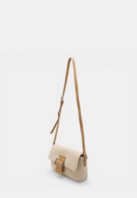 Bolso bandolera rectangular beige con tejido texturizado, una hebilla ancha en la solapa y una correa ajustable de cuero tostado.