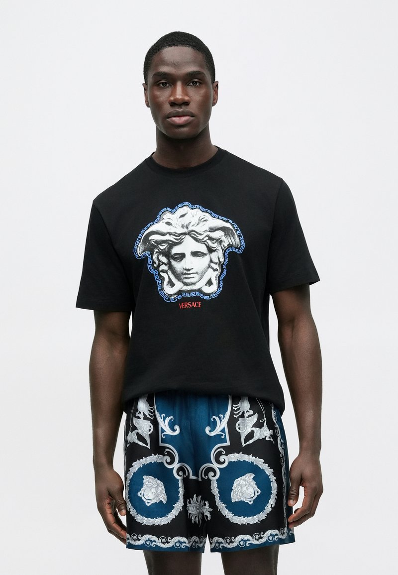 Black short-sleeve t-shirt with a decorative white and blue Medusa graphic, paired with patterned blue and black shorts showcasing ornate details.