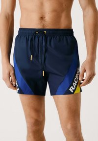 Mornarske kopalne hlače z modrimi stranskimi paneli, rumenimi poudarki, elastičnim pasom s vrvico in natisnjenim napisom "RACING."