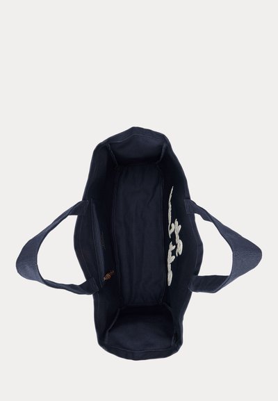 Granatowa torba na ramię z dwoma uchwytami, otwartym górnym wejściem oraz wewnętrzną boczną kieszenią na zamek, na jednolitym białym tle.