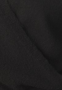 Černá pletená tkanina s měkkou strukturou. Na obrázku jsou vidět překrývajíc í se vrstvy, které zvýrazňují tloušťku a vzor pleteniny.