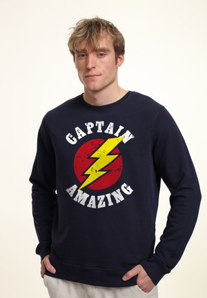 Marine sweatshirt med et cirkulært rødt grafisk design med en gul lynbolt og teksten "CAPTAIN AMAZING" i fede hvide bogstaver.