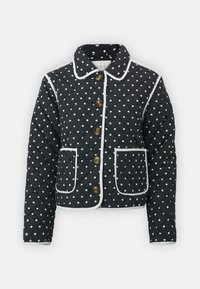 Quiltet marineblå jakke med hvite prikker, hvit piping, knappelukking og to frontlommer. Har krage.