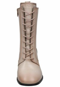 Botín de mujer de caña baja en cuero beige claro con textura suave, que cuenta con una cremallera frontal y detalles de costura en los laterales.