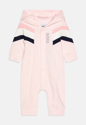 Jumpsuit infant rose avec capuche, doté d'une fermeture à boutons, rayures diagonales rose, blanche et marine, et un logo sur la poitrine.