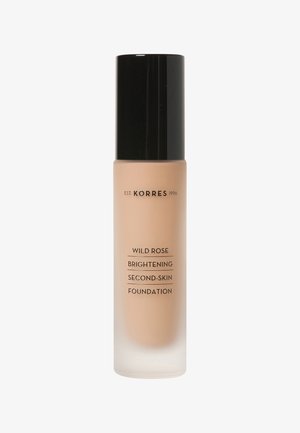 Fond de teint seconde peau éclaircissant à la rose sauvage de Korres dans un flacon en verre dépoli avec un capuchon noir. Texture lisse et crémeuse ; couleur beige clair.