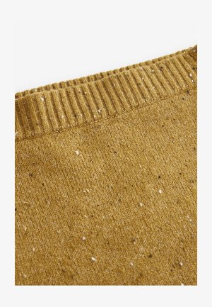 Musztardowy sweter z ribbowym dekoltem, teksturowany z flekami białego i brązowego koloru. Miękka dzianina, lekko luźny krój.