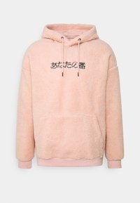 Roze fleece hoodie met een kangoeroezak, oversized pasvorm, trekkoord capuchon en zwarte tekstontwerpen op de voorkant. Zachte textuur.