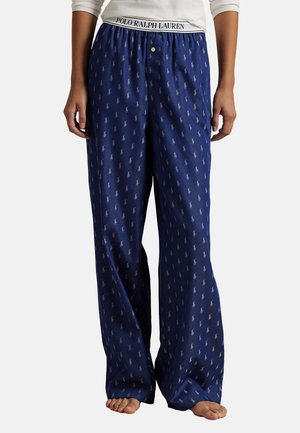 Navy blue pajama pants with a loose fit, featuring a repeating white logo pattern and an elastic waistband with a brand name.