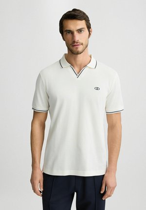 Weißes Polohemd mit V-Ausschnitt und schwarzem Saum an Kragen und Ärmeln; mit kleinem Logo auf der Brust; aus weichem Stoff gefertigt.