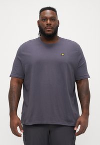 Dunkelgraues Baumwoll-T-Shirt mit kurzen Ärmeln, rundem Ausschnitt und einem kleinen gelben gestickten Logo auf der linken Brust. Glatte Textur.