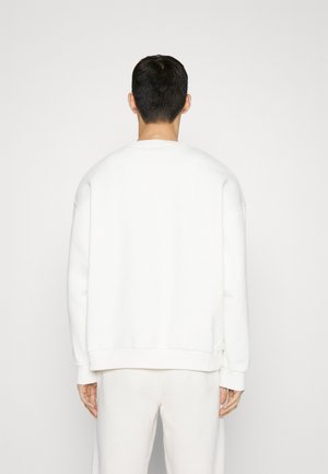 Bílé mikina s uvolněným střih, kulatým výstřihem a žebrovanými manžetami. Hladký povrch a minimalistický design, bez viditelných log.