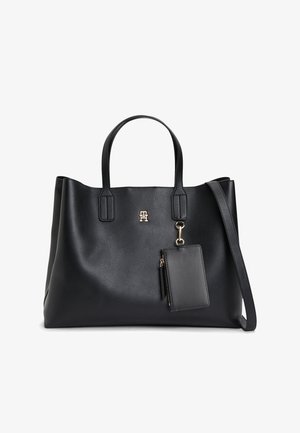 Sac cabas en cuir noir avec deux poignées, une petite poche zippée attachée, et un logo doré au centre avant.