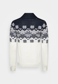 Πλεχτό πουλόβερ σε λευκό και ναυτικό μπλε, με σχέδιο νιφάδας χιονιού στο στήθος, στερεωμένο με γιακά και ραμμένα μανίκια.