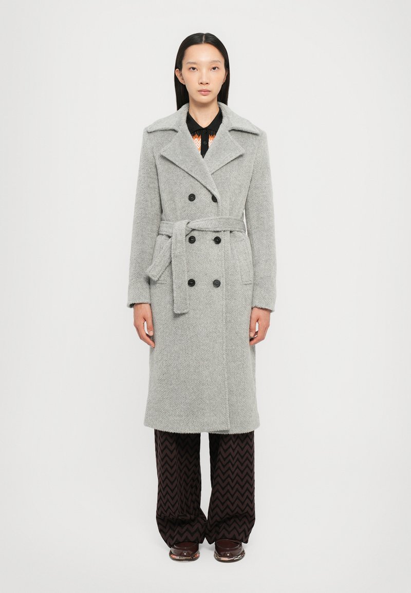 Trench coat din amestec de lână gri, cu un design cu două rânduri de butoane, guler cu tăietură, și talie cu curea. Prezintă butoane negre și buzunare laterale.