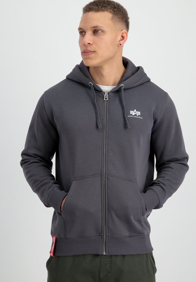 Felpa grigia con zip realizzata in tessuto morbido, dotata di un logo frontale, cappuccio con cordino e tasche a marsupio, con polsini e orlo a maglia.