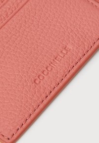 Porta-cartões em pele texturizada rosa com logótipo em relevo, costura reforçada e múltiplos slots para cartões. Acabamento suave com um design elegante.