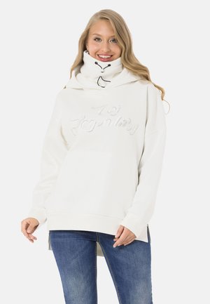 White hoodie with a high collar, drawstring accents, and "Legendary" text in a shiny, textured finish. Paired with blue jeans.