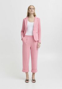 Svetlo roza tailored blazer s enim gumbom in zareznimi ovratniki, v kombinaciji z ujemajočimi se skrajšanimi hlačami z zavihanimi manšeti.