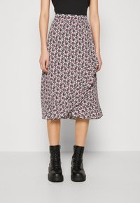 Jupe midi florale avec un fond noir, ornée de petites fleurs roses et blanches, design plissé et taille élastique. Associée à des bottines noires.