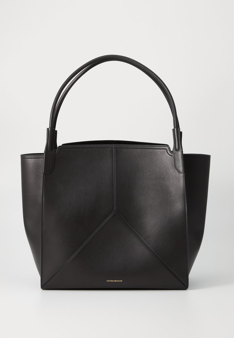 Bolsa tote de couro preto com um design geométrico, apresentando duas alças e um logotipo dourado minimalista na parte inferior. Textura suave.
