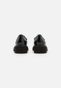 Zwarte gepatineerde leren schoenen met dikke, gestructureerde zwarte zolen. Met een ronde neus en minimale naaddetails. Achteraanzicht.