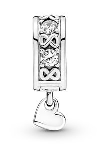 Charm plateado con tres piedras circulares transparentes y símbolos de infinito, con un colgante en forma de corazón en la parte inferior. Textura de superficie suave.