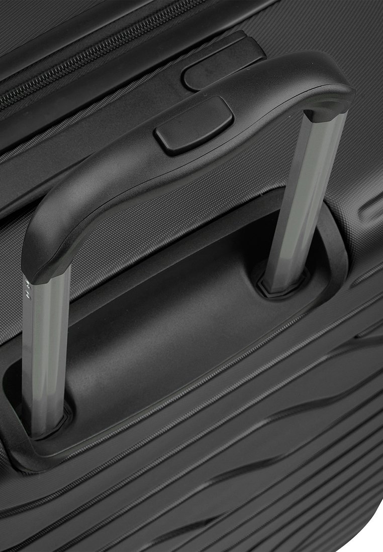 Maleta negra con ruedas que presenta un exterior texturizado, un mango retráctil de aluminio y un compartimento con cremallera. Diseño de agarre ergonómico.