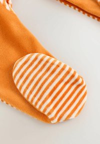 Pomarańczowa skarpetka z polaru z paskowym, miękkim spodem z frotte, z naprzemiennie ułożonymi pomarańczowymi i białymi paskami. Ogólnie gładka tekstura.