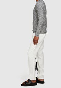 Grå texturerad långärmad tröja, vita linbyxor och svarta remsandaler. Fokus på bekväm passform och avslappnad design.