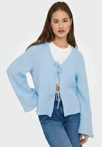 Cardigan azzurro chiaro, ampio e morbido, realizzato in tessuto testurizzato, con maniche larghe, scollo a V e lacci regolabili nella parte anteriore.