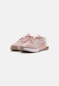 Scarpe da atletica rosa chiaro realizzate in mesh traspirante con punte tonde, lacci piatti e suole in gomma con motivi testurizzati.