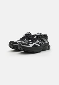 Black and silver running shoes with mesh upper, thick cushioned sole, and distinctive circular accents on the sides. Laced design on top.