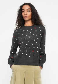 Ciemnoszary sweter z wielokolorowymi wzorami serc w odcieniach czerwieni i bieli, z długimi rękawami i okrągłym dekoltem. Teksturowany wzór dzianiny.