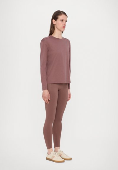 Long-sleeve mauve top with crew neckline, paired with matching fitted leggings and light-colored sneakers with a striped design.