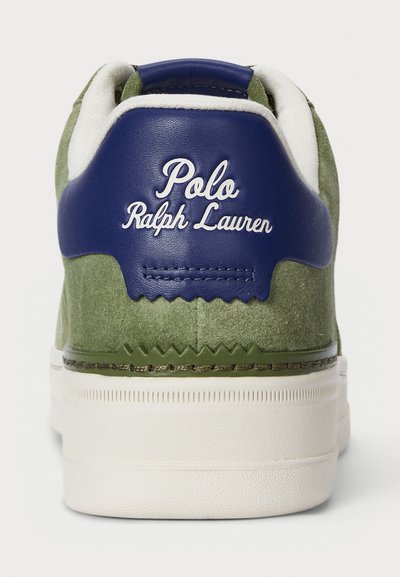 Zeleni brušeni tenis s tamnoplavim kožnim petnim dijelom, bijelim šavovima i natpisom "Polo Ralph Lauren" u stilu rukopisa. Ima teksturiranu gumenu potplat.