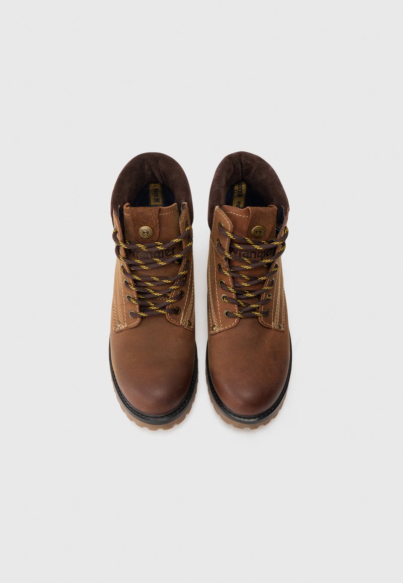 Para brązowych skórzanych butów za kostkę z miękkimi kołnierzami i żółto-paskowanymi sznurówkami na białym tle.